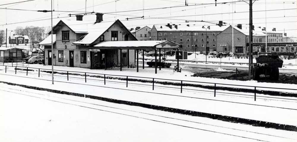 Vallentuna järnvägsstation, sedd norrifrån.  Vallentuna järnvägshotell   Flugan  har brunnit ner 1970. I bakgrunden längst t v  Vallentuna prästgård . T h om stationshuset bostadshus vid  Skördevägen  och  Vallentuna kommunalhus