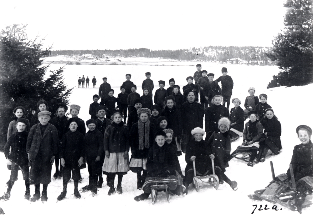 Frösunda skola   Skridskolov  på  Helgösjöns  is. En del barn har  skridskor  andra sitter på  kälkar.  I andra raden nr 1 Elna Andersson Löfgren, nr 2 Helga Andersson.  Helge Andersson finns med på bilden.  I kappa med förkläde i bildens mitt: Engla Andersson
