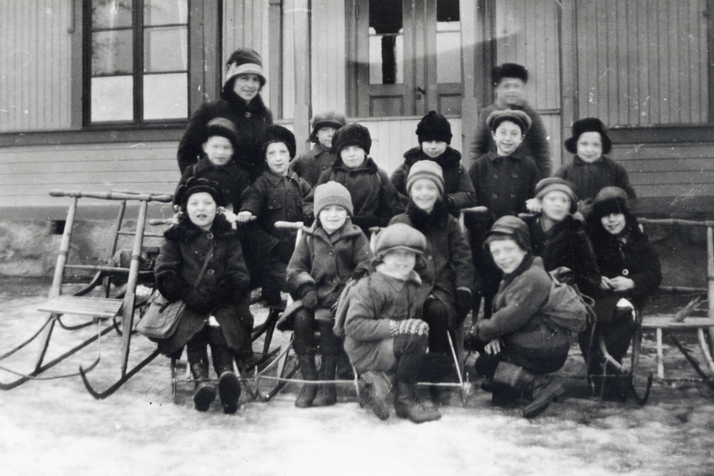 Torsholma skola i Frösunda. Barnen samlade utanför skolan med sparkstöttingar, sparkar. I övre raden står lärarinnan Elna Eriksson, gift Sandgren, framför henne fr v Arne Östervall, Stig Öhman, Henry Jansson, Birgit Roos, Svea Johansson, Erik Jansson och ovanför honom Tage Mattsson?, samt Sven Johansson (Billersjö). Mellanraden fr v Elvy Stolpe, Aina Gustavsson, Karin Karlsson,  Karin Mattsson och Magda Lindkvist.  Längst fram sitter Melker Jansson och Erik Pettersson.