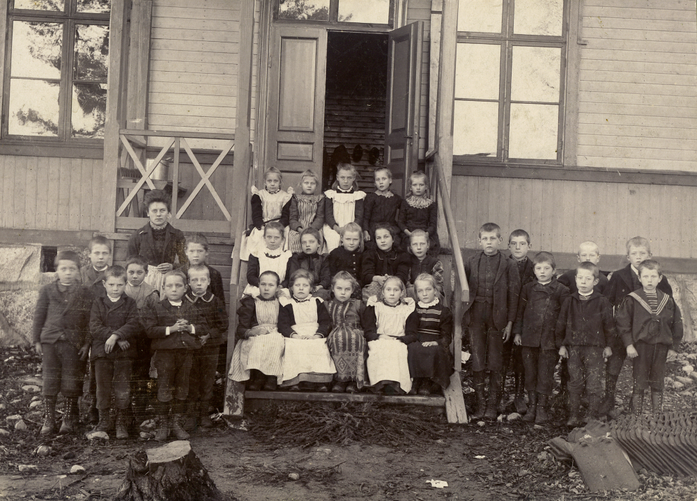 Lärarinnan Lisa Barthelsson tillsammans med skolbarnen utanför Sunnanå småskola, ca 1910, Uppgift om årtal saknas, men troligtvis ca 1906-1910. Namn på barnen saknas. Om du vet något om barnen på fotot, hör gärna av dig till bildarkivet så vi kan komplettera bildtexten.