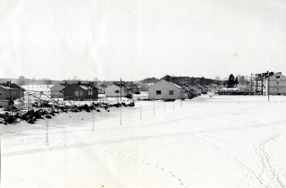 Prästgårdsgärdet  bebyggs med enfamiljshus i början av 1950-talet. Längst t v skymtar  Väsby kvarn  och t h syns flerfamiljshusen vid   Allévägen  under byggnad