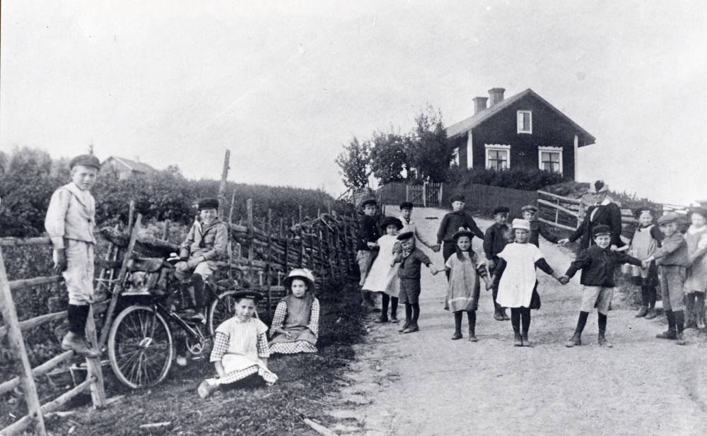 Rast vid Halls skola Pojken vid grinden heter John Pettersson. De sittande flickorna är Gerda Eriksson och Anna Smith. T h om lärarinnan Ida Högberg , som var från Kvie på Gotland, ses Anna Hansson och Martin Lindgren