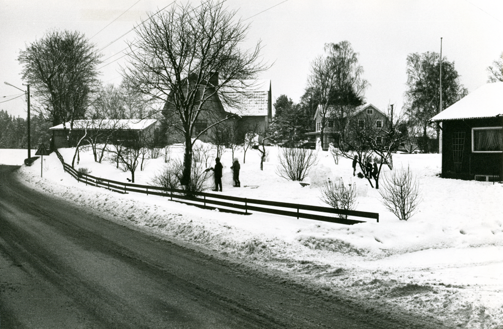 Bebyggelse vid Karlbergsvägen i Bällsta. I en trädgård leker några barn i snön.

•Fotografiet ingår i bildserien ”Vardagsliv i Vallentuna kommun” av Rachael Gough-Azmier & Gunilla Blomé, Haga Studios HB.