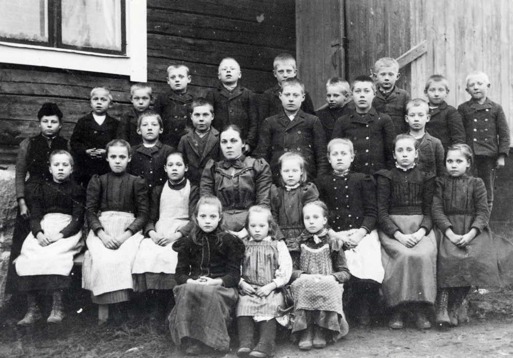 Lärarinnan Ida Högberg med skolbarnen utanför Halls skola i Kårsta, förmodligen omkring sekelskiftet