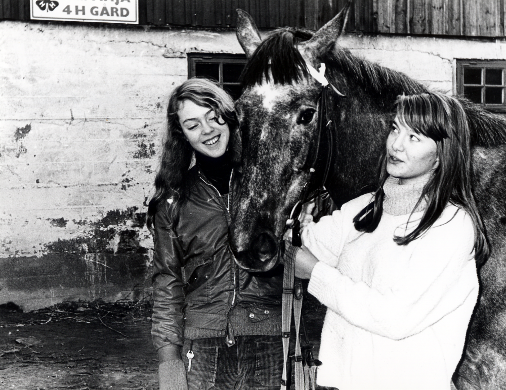 Eva Isaksson, klädd i ljus tröja, står tillsammans med varmblodsstoet Asta utanför Stall Maja, 4H-gård i Vallentuna.  T v står Christin Spibey