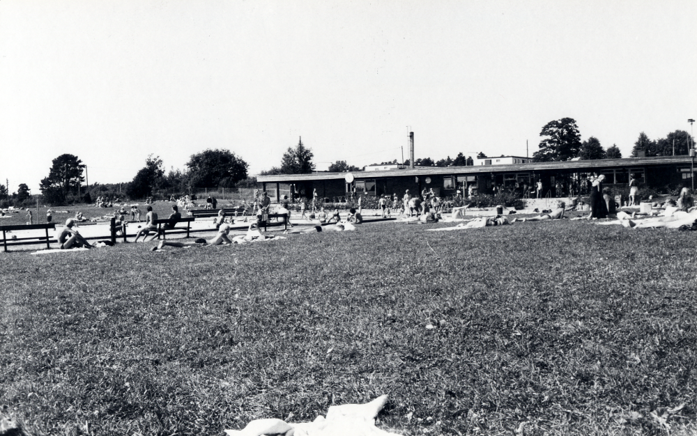 Kvarnbadet  friluftsbad med 3 bassänger vid  Väsby kvarn  och ovanför  Kyrkviken  i  Vallentunasjön  Här syns gräsmattan som omger bassängerna och t v syns den stora 50-metersbassängen. T h ligger omklädningsrum och kiosk samt reningsanläggning för bassängvattnet.