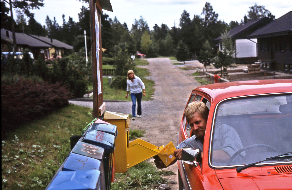 En arbetsdag med lantbrevbärare Mikael Mattsson. Lantbrevbäring i Rocksta;  Lantbrevbärare Mikael Mattsson tömmer lådan i Rocksta.  Agneta Gustavsson syns i bakgrunden.