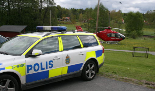 Polisbil och röd helikopter i bakgrunden