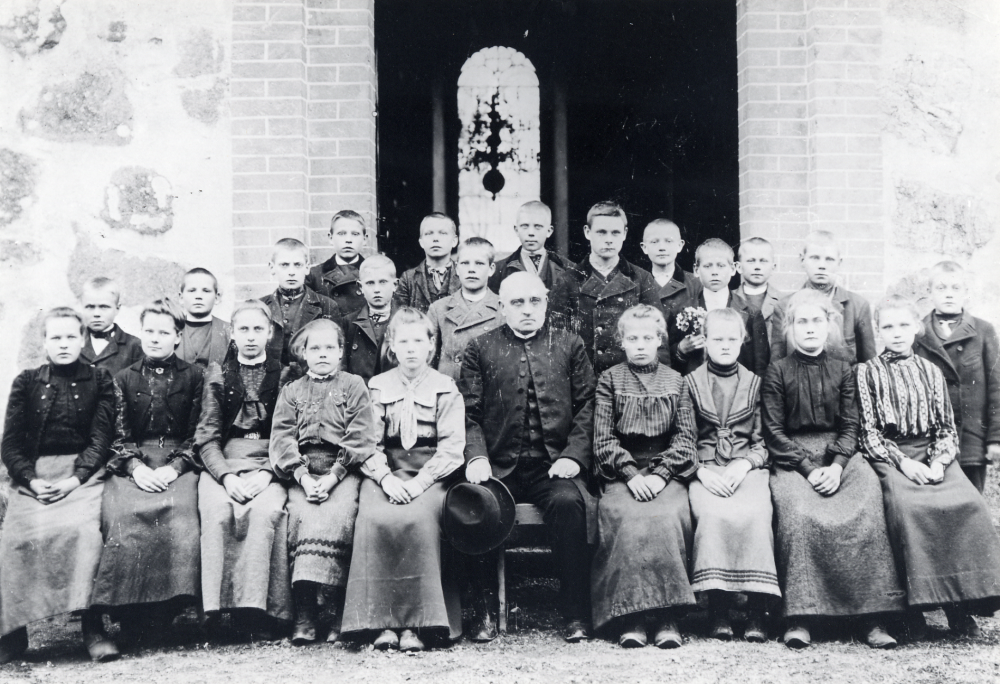 Läraren Lundberg tillsammans med skolbarnen utanför Vallentuna kyrka. Sittande i nedre raden nr 3 fr v är Anna Johansson från Oppgården