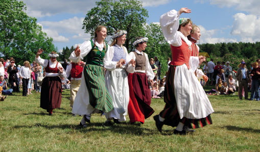 Dansare i folkdräkter på sommaräng