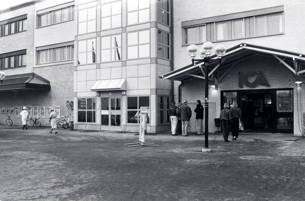 Tärningen i Vallentuna centrum har byggts ut mot norr med nya förvaltningslokaler och utökat butiksutrymme i ICA hallen, ICA Vallentuna centrum.  Här syns entrén till Tuna torg 15 och den nya ingången till ICA.  Skillnaden runt fönstren visar skarven mellan gammalt och nytt hus