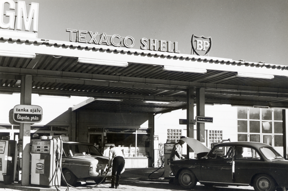 Vallentuna motor i korsningen Angarnsvägen och Industrivägen ägs av Karl och Rut Noreen. På bensinstationen finns flera märken att välja mellan och företaget är generalagent för GM, General Motors och säljer bilar bl a Opel.  Två bilar står vid bensinstationen, en Ford Taunus och en Wolkswagen