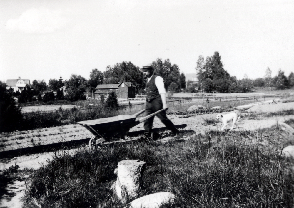 Claës Erik Schram köpte 1921 tomtmark öster om Ormsta gård för att bygga ett sommarställe.  Det fick namnet Schramsta.  Sommaren 1923 är huset färdigbyggt.  Samtidigt anlade Claës Erik Schram en trädgård med solur, blommor och fruktträd.  Här går Claës Erik med en skottkärra i den nyanlagda trädgården.  I bakgrunden syns fr v Solsta, bostad för svågern C M Carlsson och hans familj, Solstas hönshus samt Sigridslund, där C J Pettersson "Brännar-Pelle" bodde med fru och barnbarn.