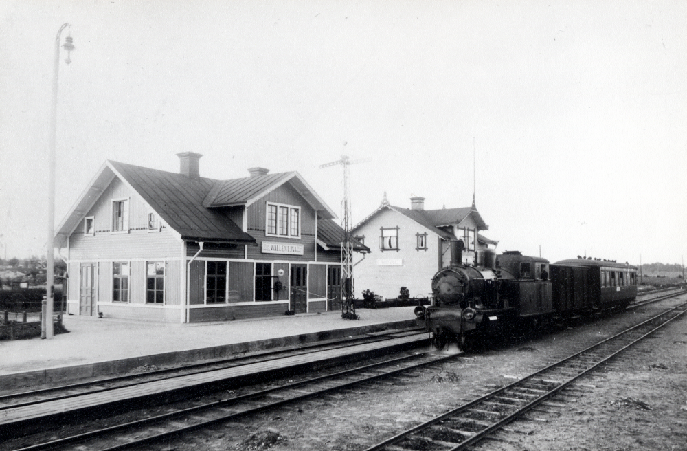 Vallentuna järnvägsstation  vid  sekelskiftet. Framför stationshuset finns en  semafor. Vid perrongen står ett  ånglok  med en  godsvagn  och en  personvagn