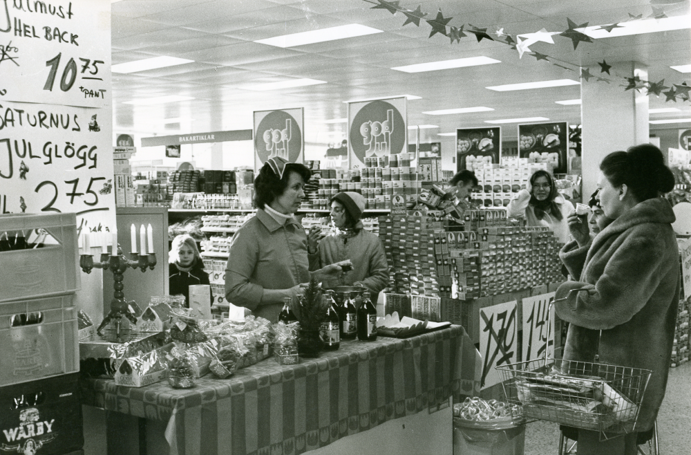 Maj-Lis Lindberg bjuder kunderna på glögg på Konsum i Vallentuna.

•Fotografiet ingår i bildserien ”Vardagsliv i Vallentuna kommun” av Rachael Gough-Azmier & Gunilla Blomé, Haga Studios HB.