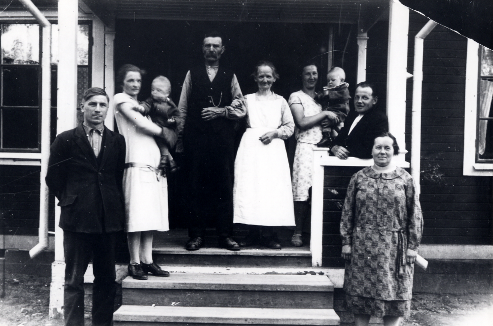 På trappan till Nils Allenius'hus Skogshyddan vid Lingsbergsvägen står fr v Hugo Bok och hans hustru Nanna Bok med lille Lars på armen, Johan Christian Allenius och hans hustru Vilhelmina, Vera Allenius med Rolf på armen och Nils Allenius samt Julia Hedlund