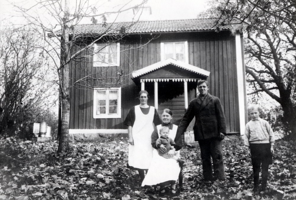 Norrgården i Gillberga, Kårsta.  Fr v på gårdsplanen Lilly Mattsson (Olga Linnéa Karolina f Kraft 11/9 1900), Josefina Kraft f Johansson 1862 med lille Karl-Uno Mattsson f 2/6 1929 i knäet, Uno Mattsson f 1/3 1906 i Össeby-Garn och fostersonen Edgar Axzell f 14/3 1924 i Stockholm.