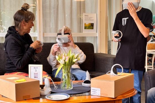 Elev från Hagaskolan prövar VR headset tillsammans med senior och samordnare för Träffpunkten