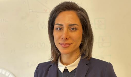 Bild på matematiklärare som håller i undervisningsbok och miniräknare.