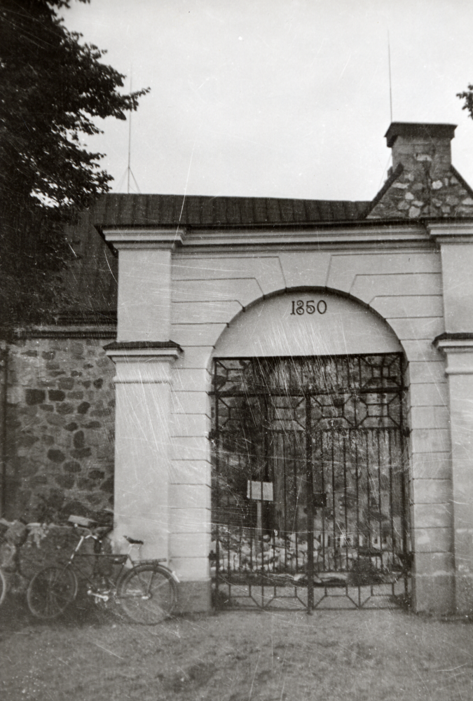 Grinden in till Vallentuna kyrka. Överdelen är nu borttagen. Den var missvisande p g a årtalet. En del besökare atrodde att kyrkan var byggd detta år. Församlingen ville ta bort hela portalen och ersätta den med grindstolpar. Det medgav inte byggnadsstyrelsen. Enligt obekräftade uppgifter skulle portalen komma från Molnby  gård