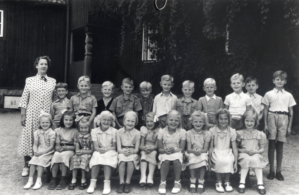 Lärarinnan Berna Nilsson med elever på examensdagen utanför Röda skolan.  I övre raden fr v står Bosse Persson (Wilén),  Lars-Erik "Lasse" Karlsson, Gunnar Ekström, Hans Gustavsson, Stig-Arne Brunn, Lars-Erik Grip, Leif Brodd, Sören Gustavsson, Hans-Åke Engström och Tor Hallenberg.  Sittande fr v Margareta Bladlund, Anita Broman, Neta Danred, Birgitta Johansson, Sally Andersson, Margot Johansson, Berit Frölin, Eva Hahn, Anna-Lena Bengtsson och Gunhild Andersson.  Birgitta Ekström var sjuk!
