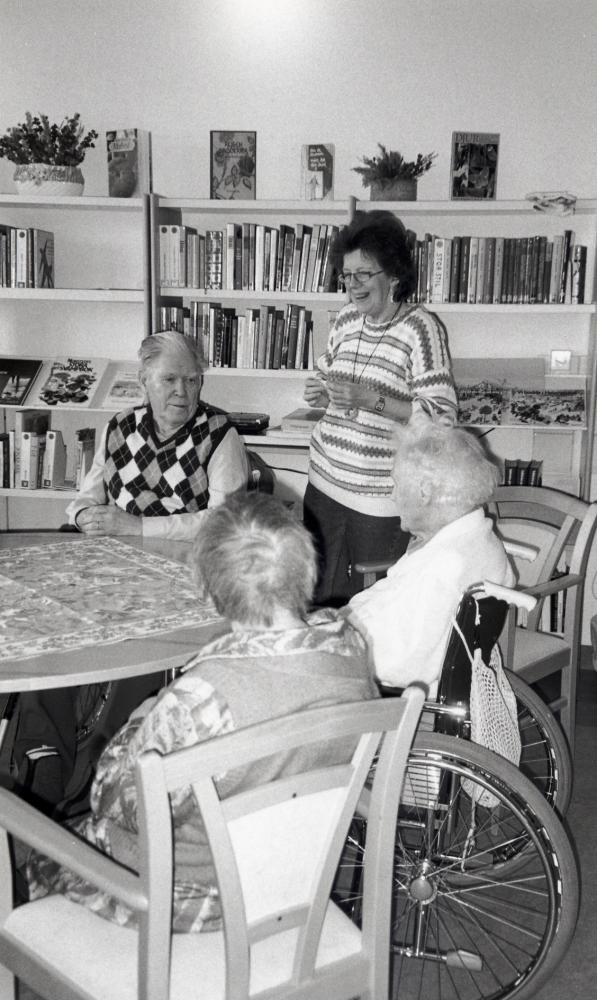 Ulla-Britt Kvarnestam från Vallentuna bibliotek besöker varje vecka sjukhemmet Korallen och ger de boende och personal möjlighet att låna böcker och talböcker.  En liten samtalsgrupp samlas också och diskuterar något aktuellt ämne och Ulla-Britt l läser ett stycke ur någon bok.  Runt bordet sitter fr v Elsa Karlsson, Ebba Bjursell och Åke Ekstedt.