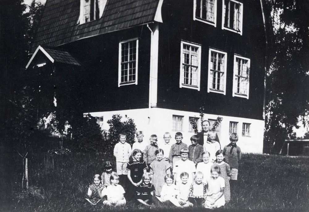 Lärarinnan Signe Östman tillsammans med skolbarnen utanför Åvasta skola. Övre raden fr v Gunnar Laurell, Harald Jansson, Nils Hermansson, Bertil Larsson, Einar Larsson, Erik Hermansson, Tore Melin och Henry Roos. Knästående fr v Einar Möller, Svea Öhman, Dagny Lundgren, Karin Nyberg och Karin Hermansson. Sittande fr v Anna-Lisa Fröman, Svea Johansson, Asta Fredin?, Eva? Möller, Gullan Laurell, Stella Öhman, Lilly Nyberg och Inga-Lisa Gustavsson. Uppgifter från Ingegärd och Stig Öhman, Åttesta