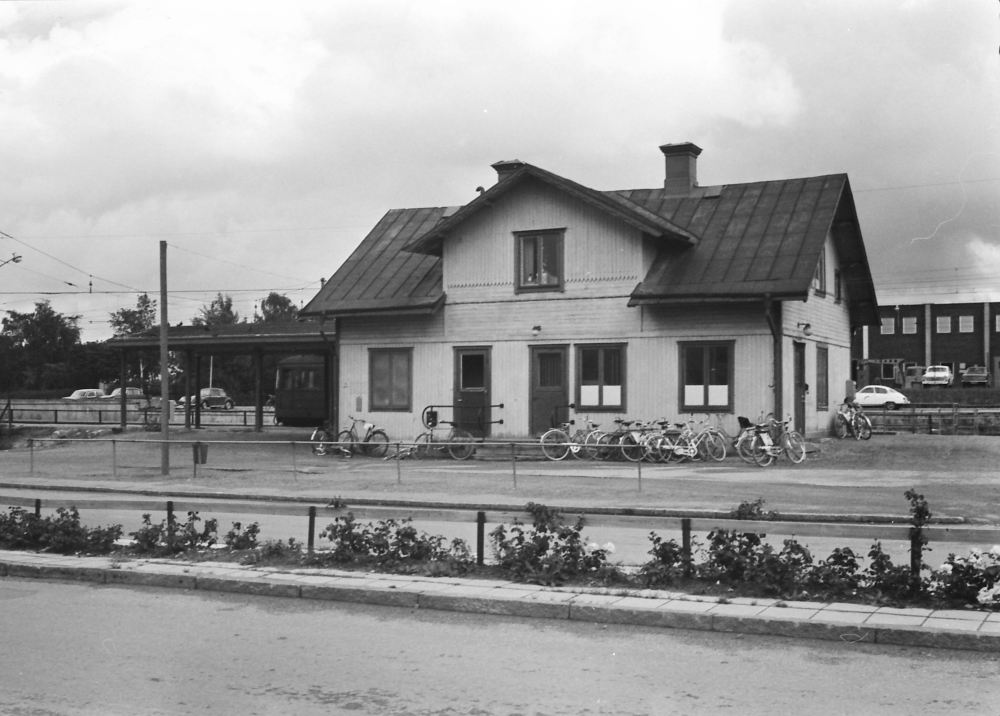 Vallentuna stationshus med Banvägen i förgrunden. Till höger skymtar Tellus Maskin AB.

•Fotografiet ingår i bildserien ”Vardagsliv i Vallentuna kommun” av Rachael Gough-Azmier & Gunilla Blomé, Haga Studios HB.