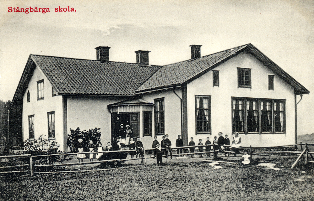 Stångbärga (Stångberga) skola i Össeby-Garn.  I skolhusets dörröppning står två kvinnor. Kopia av vykort.