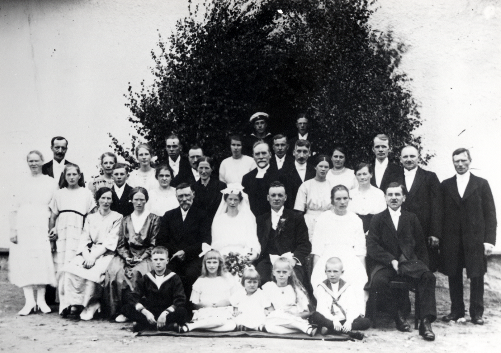 Bröllopsgästerna samlade utanför Österlid . Bakom brudparetstår kyrkoherde Östman Personer i nr-ordning (se numrering på reg.kortets baksida). 1 Albert Carlsten , 2 Rudolf Balck , 3 Ejnar Boman , 4 J Elfving 5 Ture Pettersson 6 Andrea Pettersson 7 Helmer Ohlin 8 herr Kalén 9 fru Kalén 10 herr Lundkvist 11 fru Lundkvist 12 Petrus Carlsten 14 Ruth Österlund 15 Oskar Österlund 16 Berna Carlsten 17 Erik Gustavsson 18 Tyra Lindkvist 19 Hanna Ohlin 20 kyrkoherde Östman 21 Karin Balck 22 Naemi Karlsson 23 Maria Karlsson 24 Albert Karlsson 25 Sara Gustavsson 26 Arnold Gustavsson 27 Sigrid Gustavsson 28 Birger Gustavsson 29 Lars Österlund 30 Ruth Elfving 31 Ella Österlund 32 Lennart Ohlin 34 Sonja Carlsten