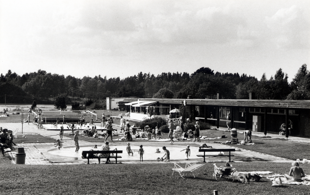 Kvarnbadet, friluftsbad i Vallentuna den mycket varma sommaren 1994.  Här syns barnbassängen, undervisningsbassängen och byggnaden med maskineri t v och kiosk med kontor t h.  En stor 50-meters bassäng samt byggnad med omklädningsrum och bastu finns också