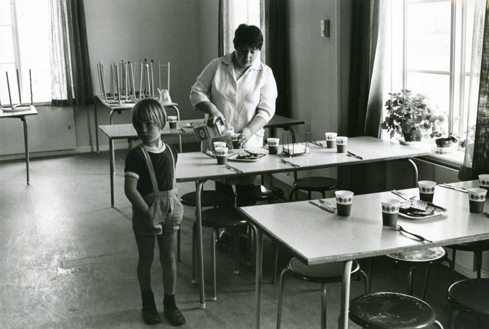 Össeby-Garns skola, dokumenterad en av de sista dagarna innan skolverksamheten läggs ner. Skollunchen serveras av Solveig Dahlbeck i f.d Össeby kommuns kommunalkontor. Solveig bor i huset. Med på bild är sonen Johan 7 år.
•Fotografiet ingår i bildserien ”Vardagsliv i Vallentuna kommun” av Rachael Gough-Azmier & Gunilla Blomé, Haga Studios HB.
