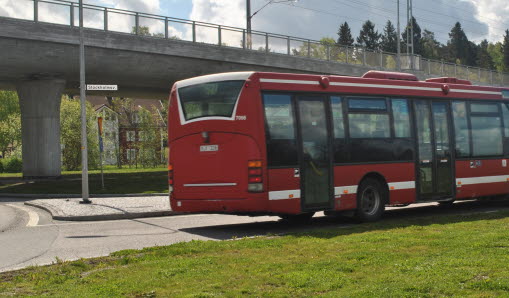 Röd buss kör längs vägen.