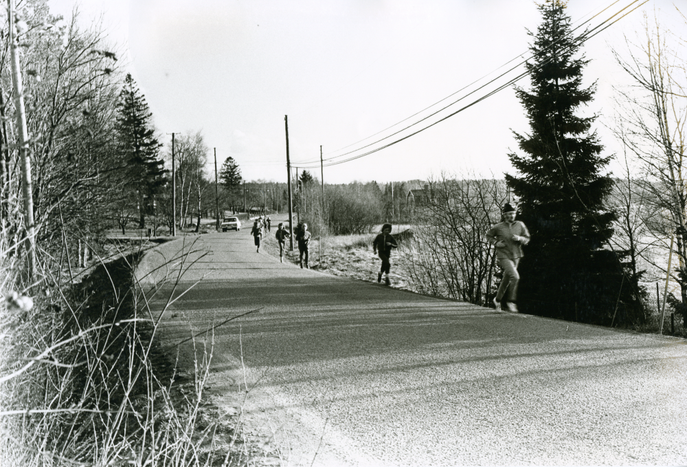 En lärare och elever springer på vägrenen mellan idrottsplatsen och Ormstaskolan.
•Fotografiet ingår i bildserien ”Vardagsliv i Vallentuna kommun” av Rachael Gough-Azmier & Gunilla Blomé, Haga Studios HB.