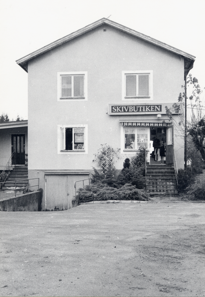 Skivbutiken i hörnet av Allévägen och Mörbyvägen.  Här har tidigare K E Karlsson sålt elektriskt material. I fastigheten finns också lägenheter, K E Karlssons son Lennart bor 1993 i en del av huset