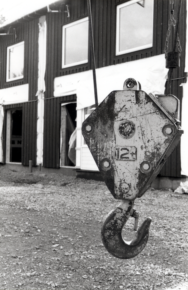 Ett nytt bostadsområde byggs i södra Vallentuna – Bällstaberg vid Kragstalunds järnvägshållplats.  En krok från en lyftkran hänger framför de ännu ej färdiga husen i september 1996