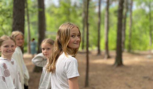 Ett gäng tjejer leker ute på skolgården i skogen