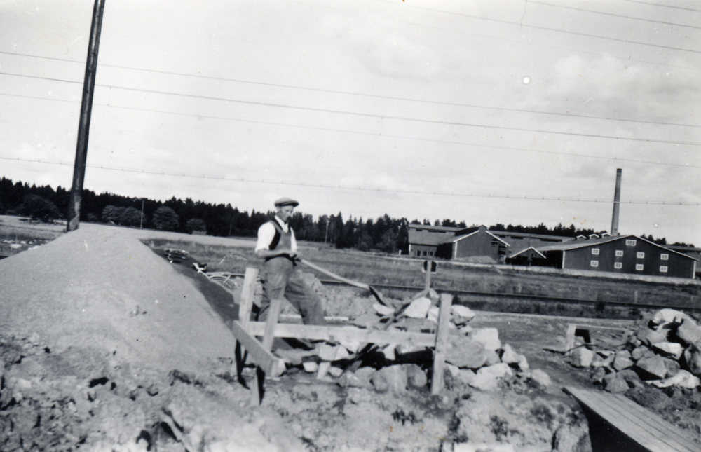 Bertil Persson har köpt tomten i hörnet av Banvägen och Svedjevägen i Vallentuna.  Här pågår grundläggningsarbeten. Huset får adressen Banvägen 25.   I bakgrunden syns Åby tegelbruk.  Familjen besetod av Bertil och hans hustru Daga, samt barnen Lilly, Kerstin och Bo