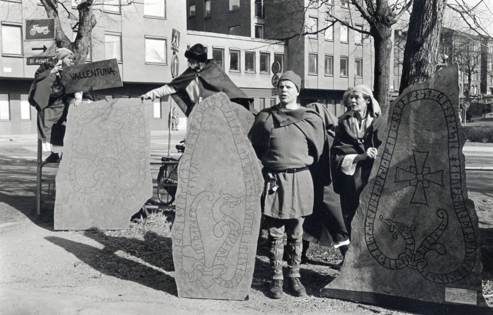 Vallentuna kommun presenterar sig på Narvavägen i Stockholm utanför Historiska museet i samband med utslätningen Den svenska historien. Fr v i bakgrunden står Inger Olssonoch Alf Olsson i pälsmössa., vid avbildningen av runsten U 329 står Gurli Hamilton.   T v står en okänd vikingaklädd man + avbildning av runsten U 344 samt längst t v U 226, en avbildning av en av stenarna vid Arkils tingstad