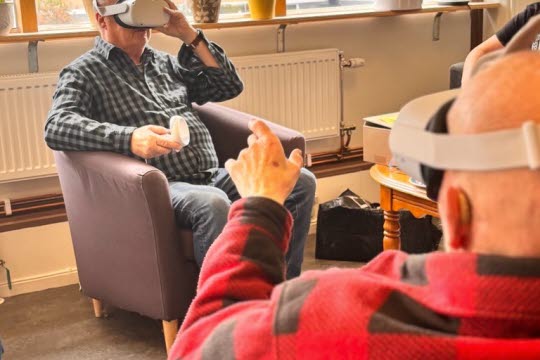 Två seniorer provar elevernas VR headset.