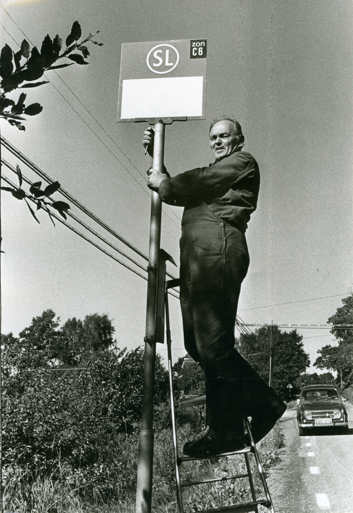 Evald Hammar från SL sätter upp nya skyltar för kommande busslinje på Åbyholmsvägen. 
•Fotografiet ingår i bildserien ”Vardagsliv i Vallentuna kommun” av Rachael Gough-Azmier & Gunilla Blomé, Haga Studios HB.