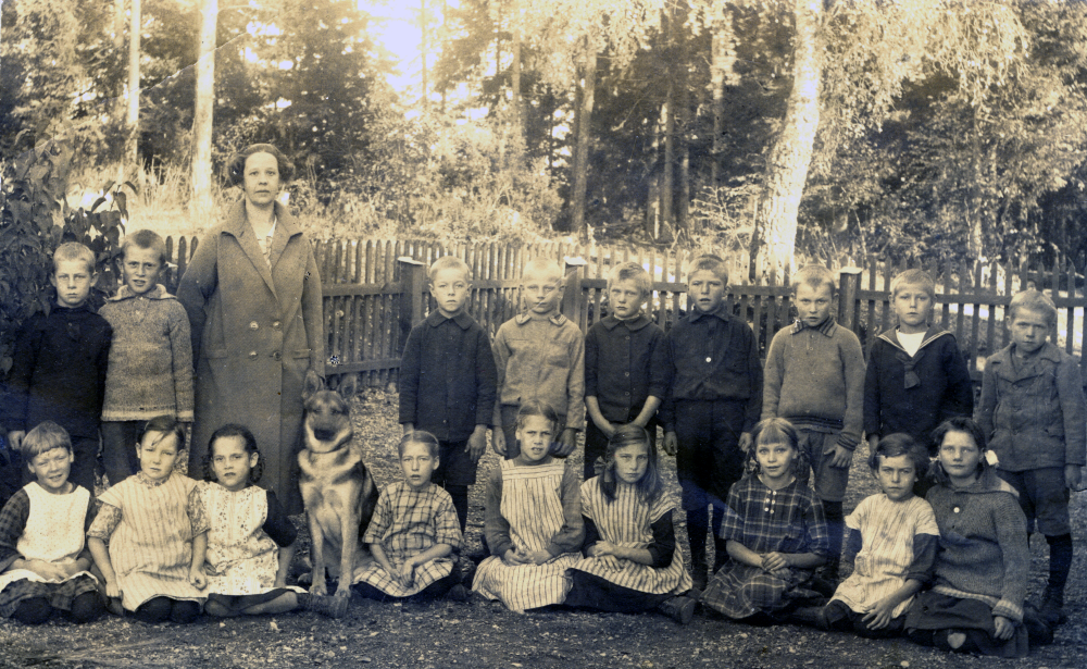 Lärarinnan Berna Nilsson med sin klass utanför Veda skola. Märta Eriksson sitter som nummer två från vänster. Bernas hund sitter sitter som nummer fyra från vänster.