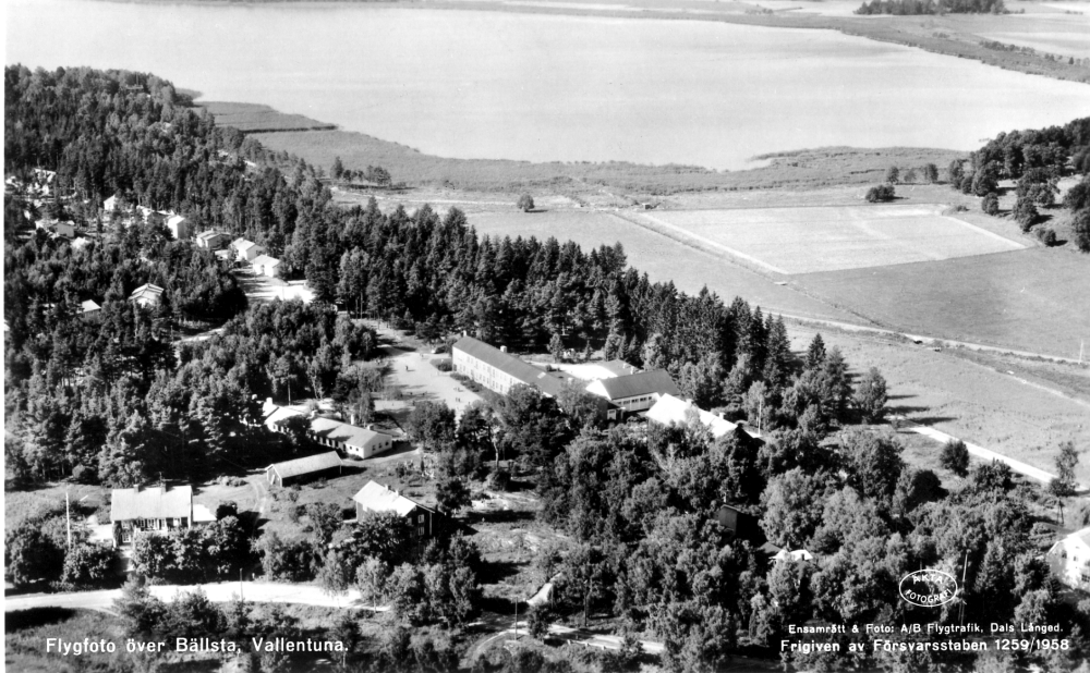 Flygfoto över Bällsta med Hjälmsta skola i bildens mitt.  I bakgrunden syns Kyrkvägen i Valletunasjön.  Från skolan i bildens mitt mot vänster syns Lagmansvägen.  I förgrunden t v Vallentunas gamla och nya ålderdomshem vid Skolvägen.  Öster om skolans mot åkermarken är ännu inte Stockholmsvägen byggd.  Roslagsbanans spår syns korsa ån på en bro