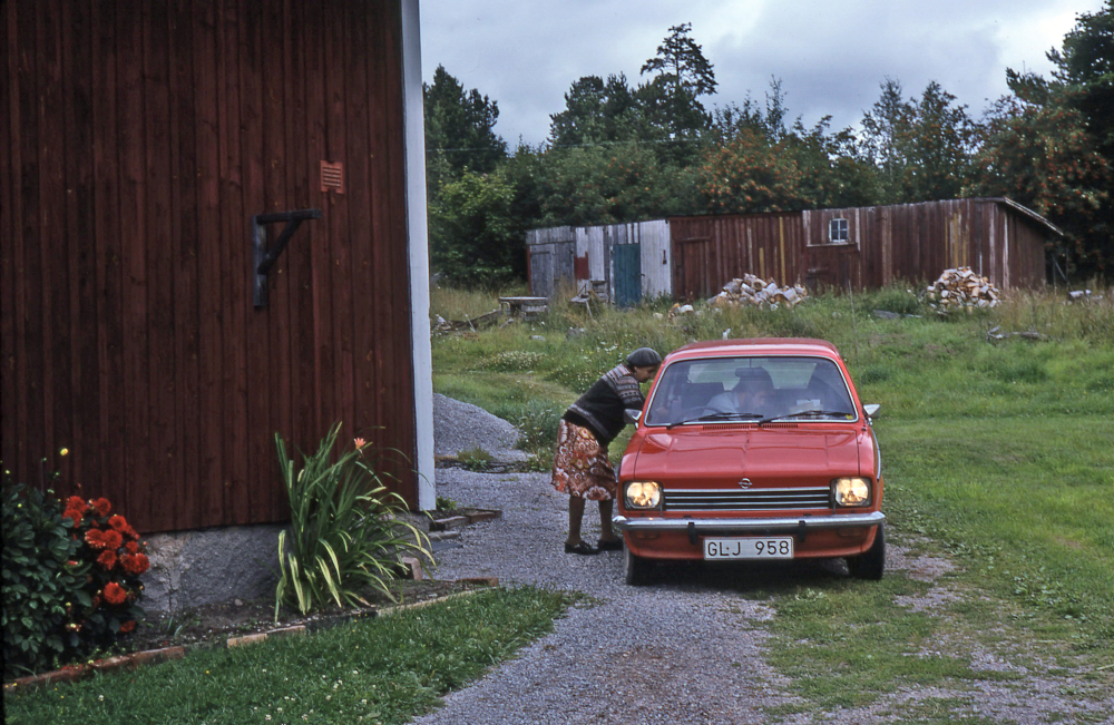 En arbetsdag med lantbrevbärare Mikael Mattsson. Lantbrevbäring i Vågsjö;  Elsa Wanzelius i Vågsjö, Täby, samtalar med lantbrevbärare Mikael Mattsson som sitter i sin bil. I bakgrunden syns ett uthus/vedbo. 