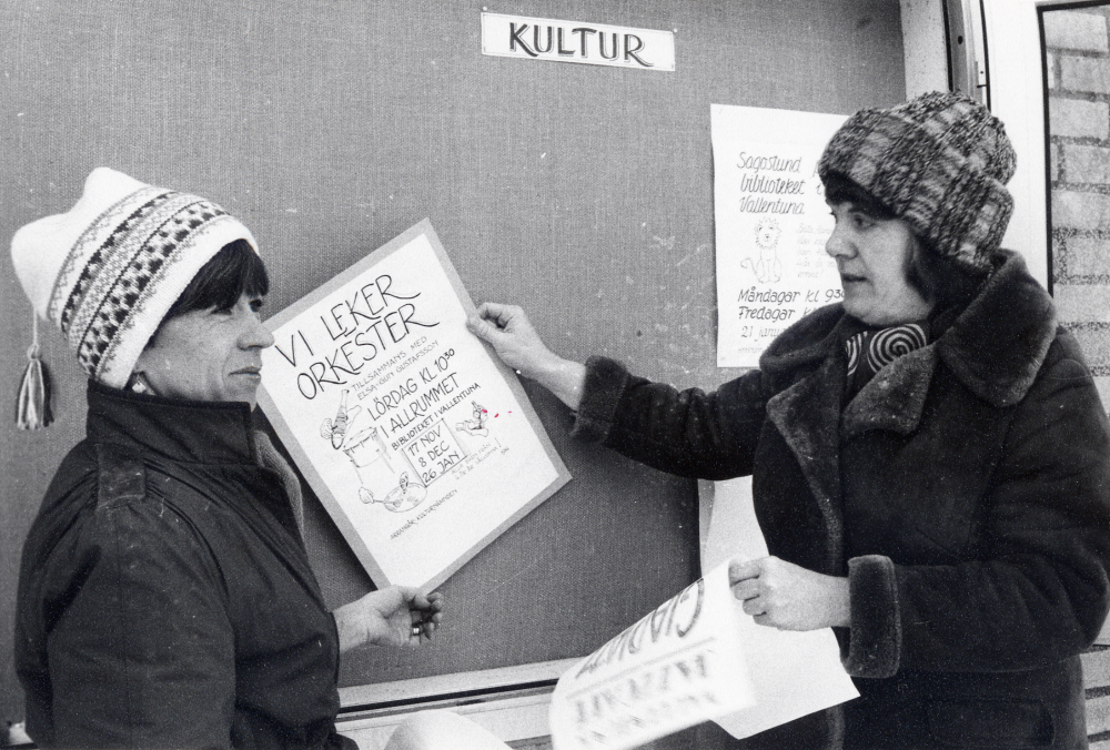 Pirkko Mickelsson t v och Eva Larsson från Vallentuna bibliotek resp Vallentuna kulturkansli skyltar om i skyltskåpet på Torghuset vid Tuna torg med flygblad från kulturnämndens programverksamhet