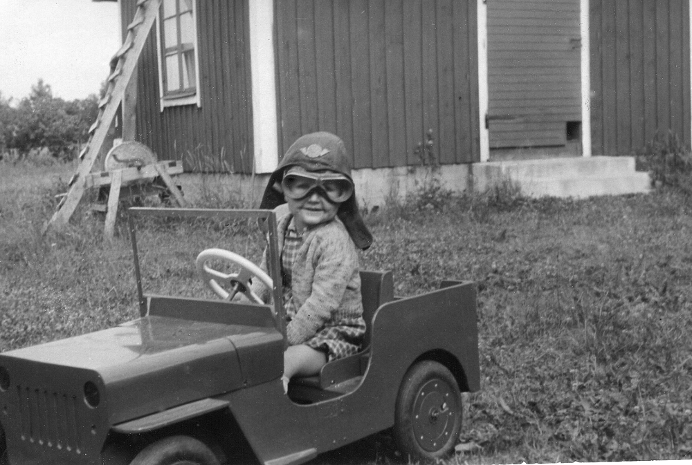 Gunnar Pettersson, son till Maj och Ragnar Pettersson, sitter i sin elektriska bil.  Bilen har Ragnar tillverkad åt sin son.  Huset i bakgrunden är familjens bostad, Björkhult i Ormsta vid Lindholmsvägen i hörnet av Ormstavägen och Hagavägens nuvarande infart.  På dess plats står 2000 en nybyggd villa. 1952 flyttade familjen Petersson till Björknäs på Olsborgsvägen