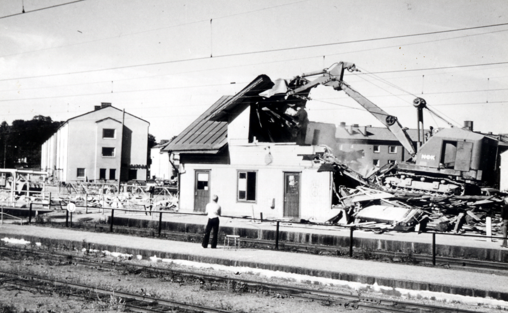 Vallentuna järnvägsstation rivs. I bakgrunden syns t v bostadshusen vid Centralvägen med konditoriets skylt på gaveln