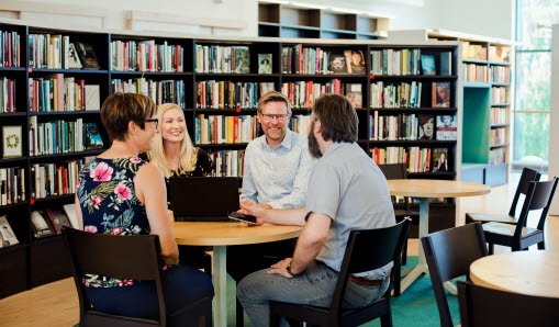 En grupp medarbetare sitter i biblioteket runt ett bord