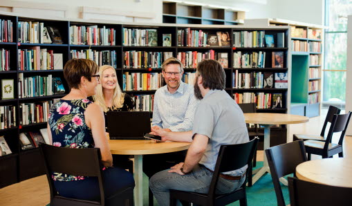 Medarbetare sitter runt bord i biblioteket