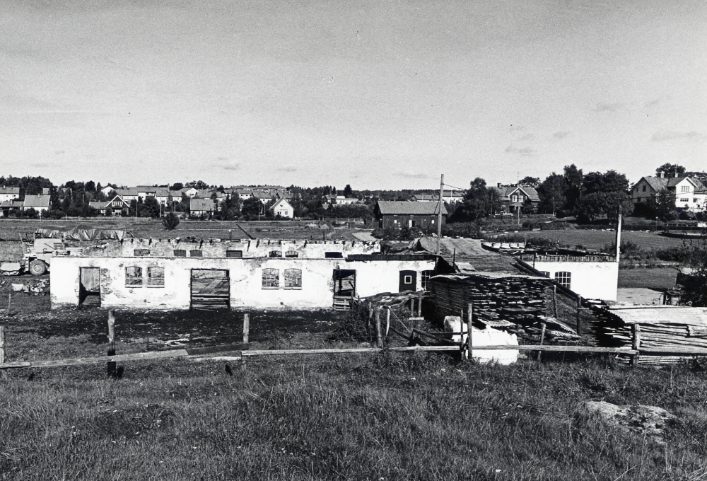 Ladugården vid Vallentuna prästgård har brunnit ner. Endast murarna finns kvar. I bakgrunden Prästgårdsgärdet Den vita byggnaden är Pastorsexpeditionen och det röda huset t v därom är arrendatorsbostaden